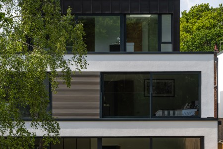 Close up view from garden of zinc clad, white rendered, glass frontage contemporary houses designed